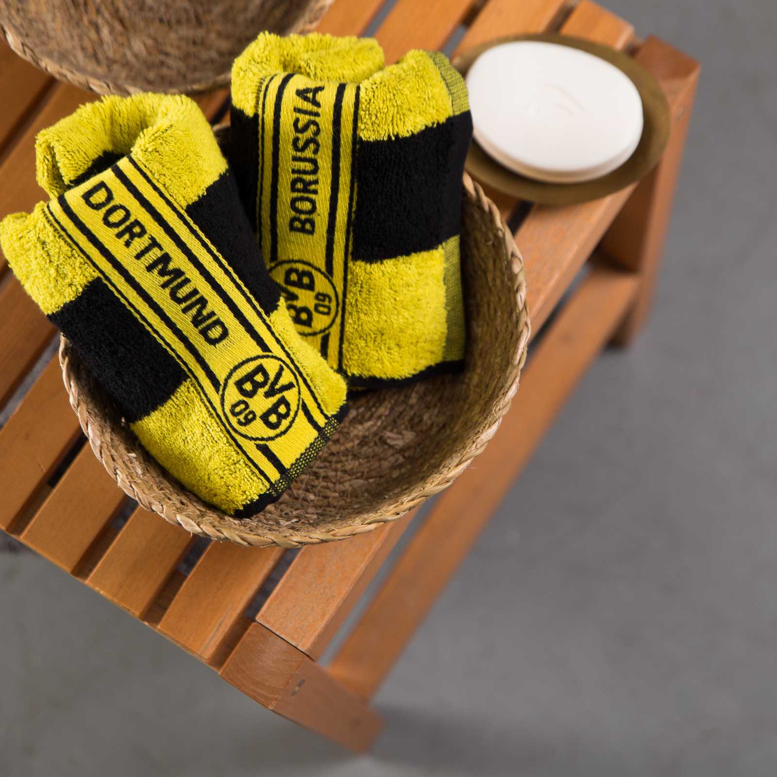 Zwei BVB-Gästehandtücher Blockstreifen im schwarzgelben Design mit BVB-Emblem, zusammengerollt in einer Korbschale, Detailansicht.