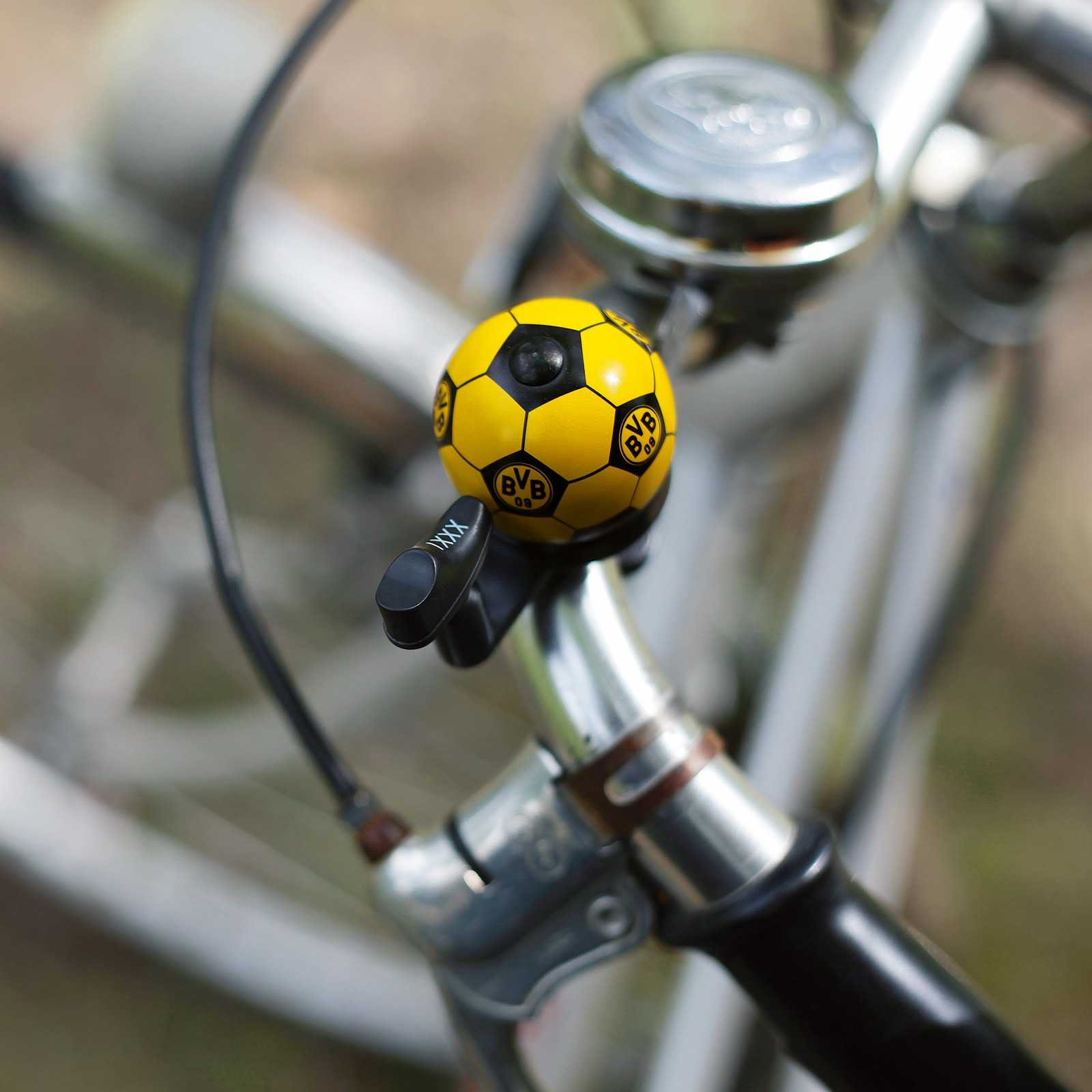Detailansicht der schwarzgelben BVB-Fahrradklingel in Fußball-Optik mit BVB-Emblem, montiert am Lenker eines Fahrrads.