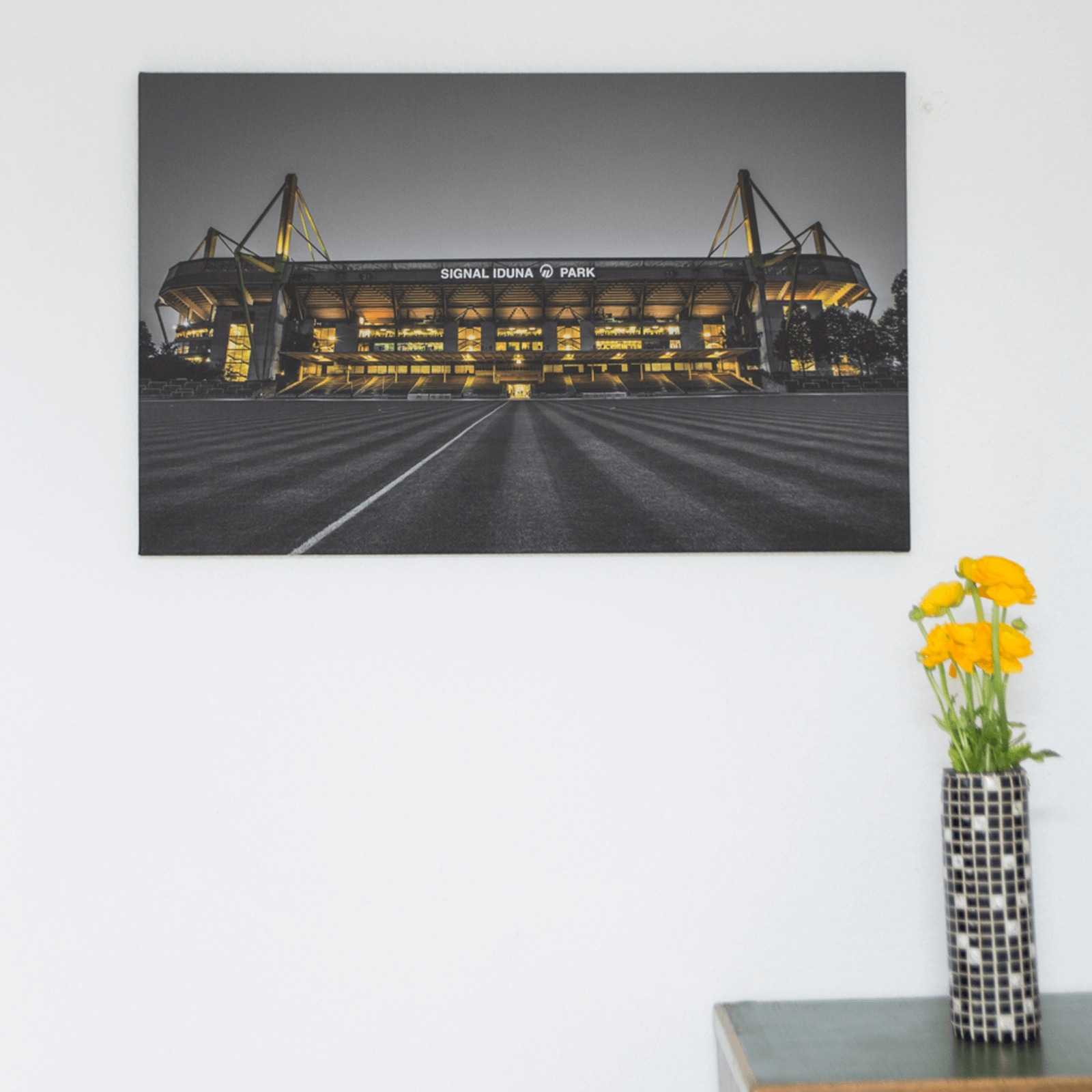 BVB-Kunstdruck SIP 80x50 cm an der Wand, zeigt den SIGNAL IDUNA PARK in schwarzgelber Beleuchtung aus frontaler Perspektive.