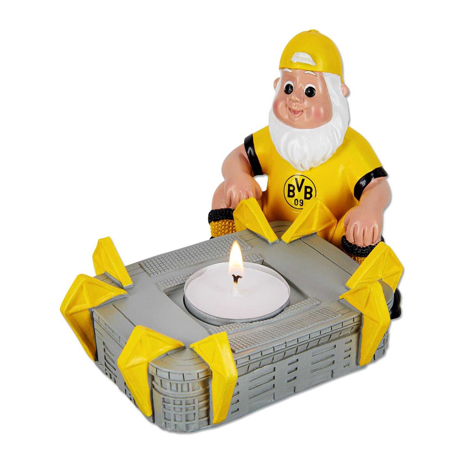 BVB Gartenzwerg mit Teelicht, sitzend in schwarzgelbem Outfit mit BVB-Emblem auf dem Shirt, hält ein Teelicht in SIGNAL IDUNA PARK-Form. Vorderansicht.