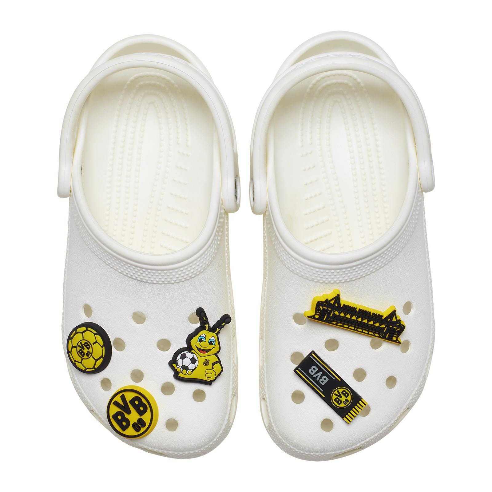 Draufsicht auf weiße Crocs mit fünf BVB Crocs Jibbitz (5er Pack), darunter das BVB-Emblem, EMMA, SIGNAL IDUNA PARK und weitere schwarzgelbe Motive.