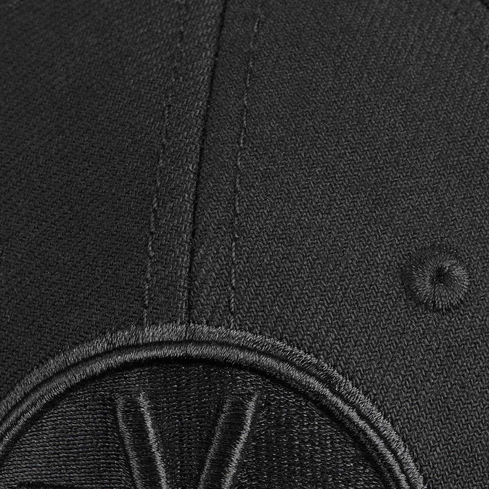 Detailansicht der BVB Cap Logo schwarz mit gesticktem BVB-Emblem in Schwarz auf schwarzem Stoff. Hochwertige Verarbeitung deutlich sichtbar.