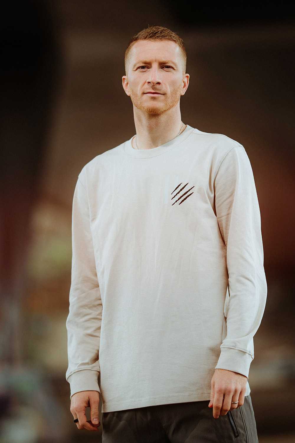 Eine Person trägt das Longsleeve MR11 in der Vorderansicht; das helle Shirt zeigt ein schwarzes Krallendesign auf der Brust, ohne sichtbares BVB-Emblem.