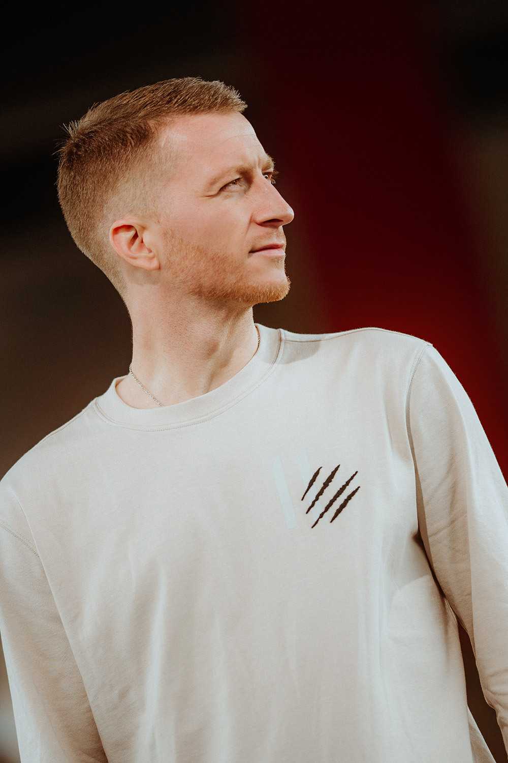 Frontansicht eines Mannes, der das beigefarbene Longsleeve MR11 mit Krallenmotiv auf der Brust trägt. Das BVB-Emblem ist nicht sichtbar.