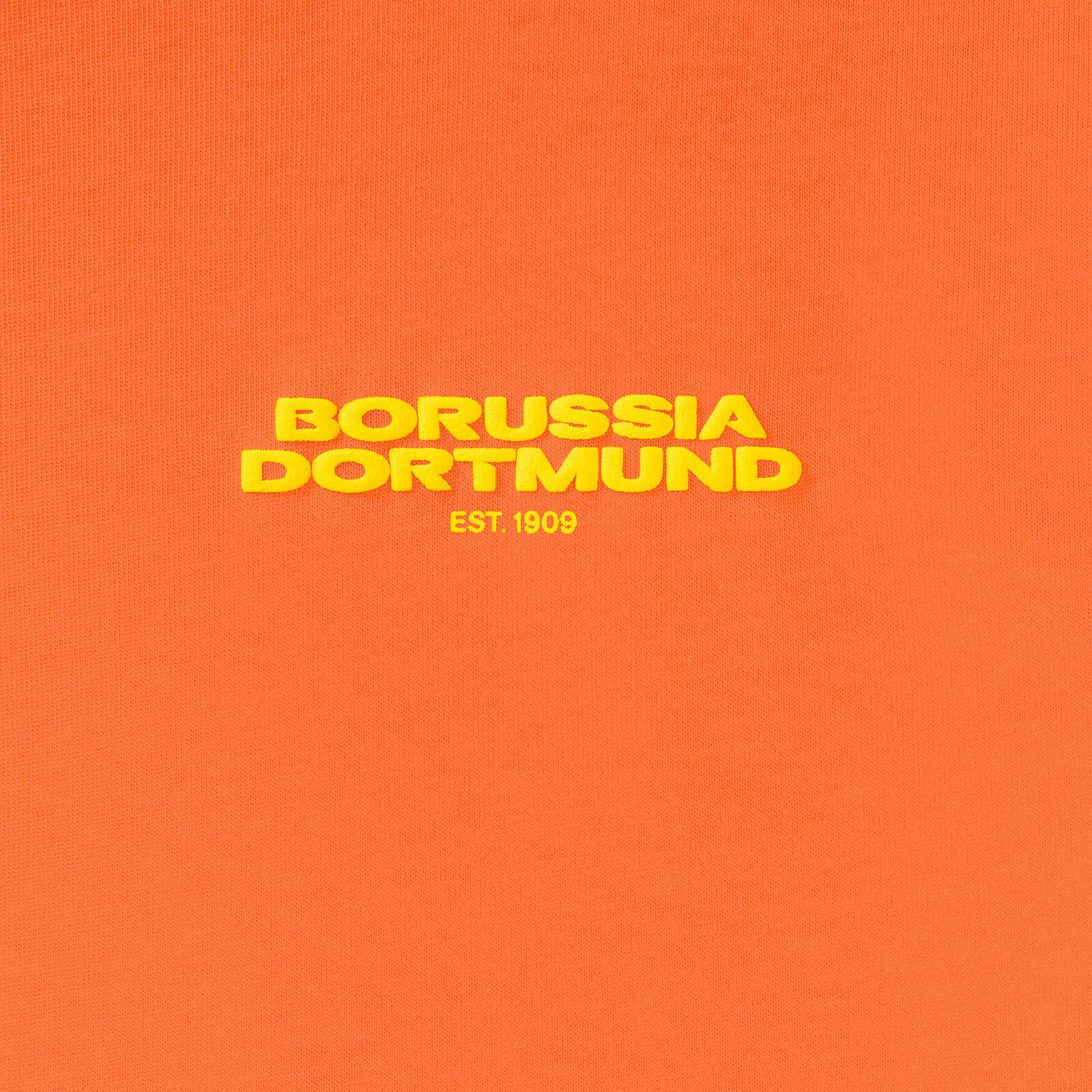 Detailansicht des orangefarbenen BVB Urban Tee mit gelbem "Borussia Dortmund EST. 1909" Schriftzug auf der Brust.