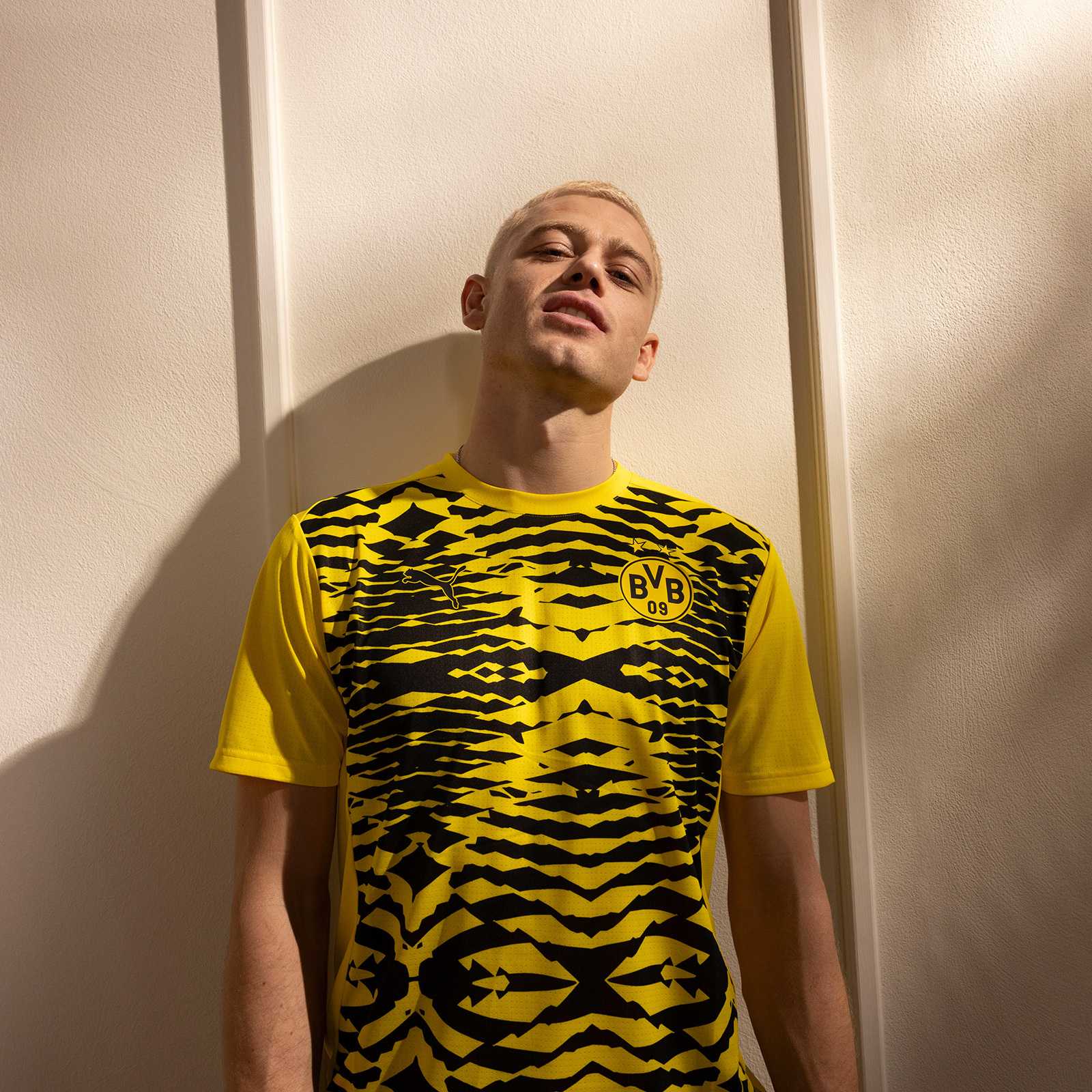 Ein Mann trägt das BVB Prematch Shirt schwarzgelb in der Vorderansicht mit auffälligem Muster, BVB-Emblem und Puma-Logo auf der Brust.