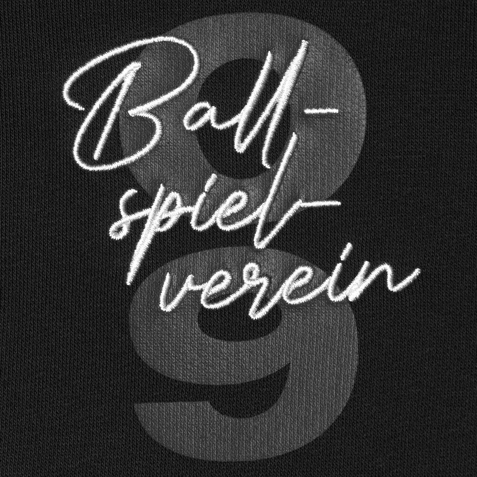 Detailansicht des BVB Elements Zip-Sweater mit gesticktem Schriftzug „Ballspielverein“ in Weiß und großer, grauer „09“ im Hintergrund auf schwarz.