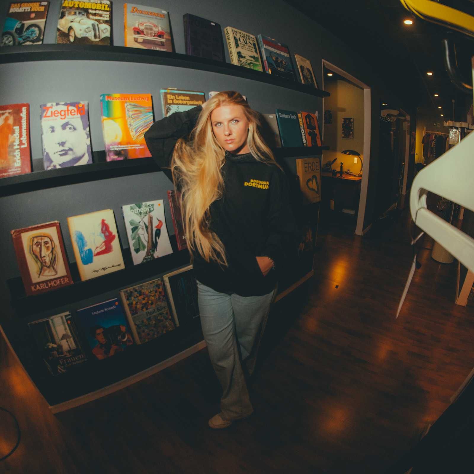 Eine Frau trägt den BVB Retro Hoodie schwarz in Frontalansicht; gelber "Borussia Dortmund"-Schriftzug sichtbar auf der Brust.