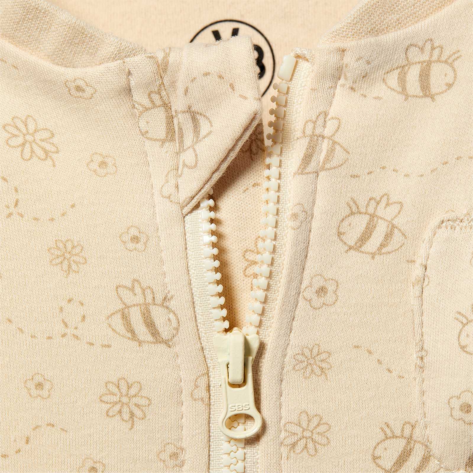 Detailansicht des BVB Schlafanzugs Baby in Beige mit Blumen- und Bienenmuster sowie sichtbarem Reißverschluss und BVB-Emblem im Nackenbereich.