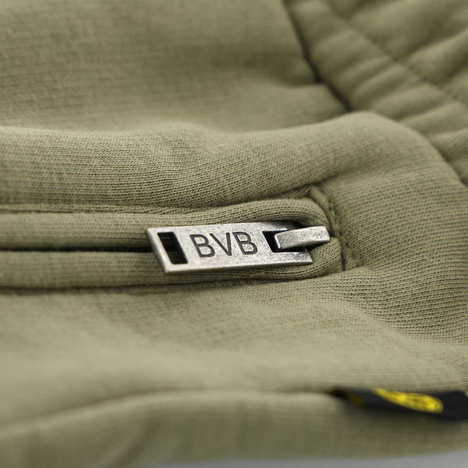 Detailansicht der BVB Sunrise Sweatshorts in Beige mit einem silbernen Reißverschluss, auf dem "BVB" steht, und kleinem BVB-Emblem am Rand.