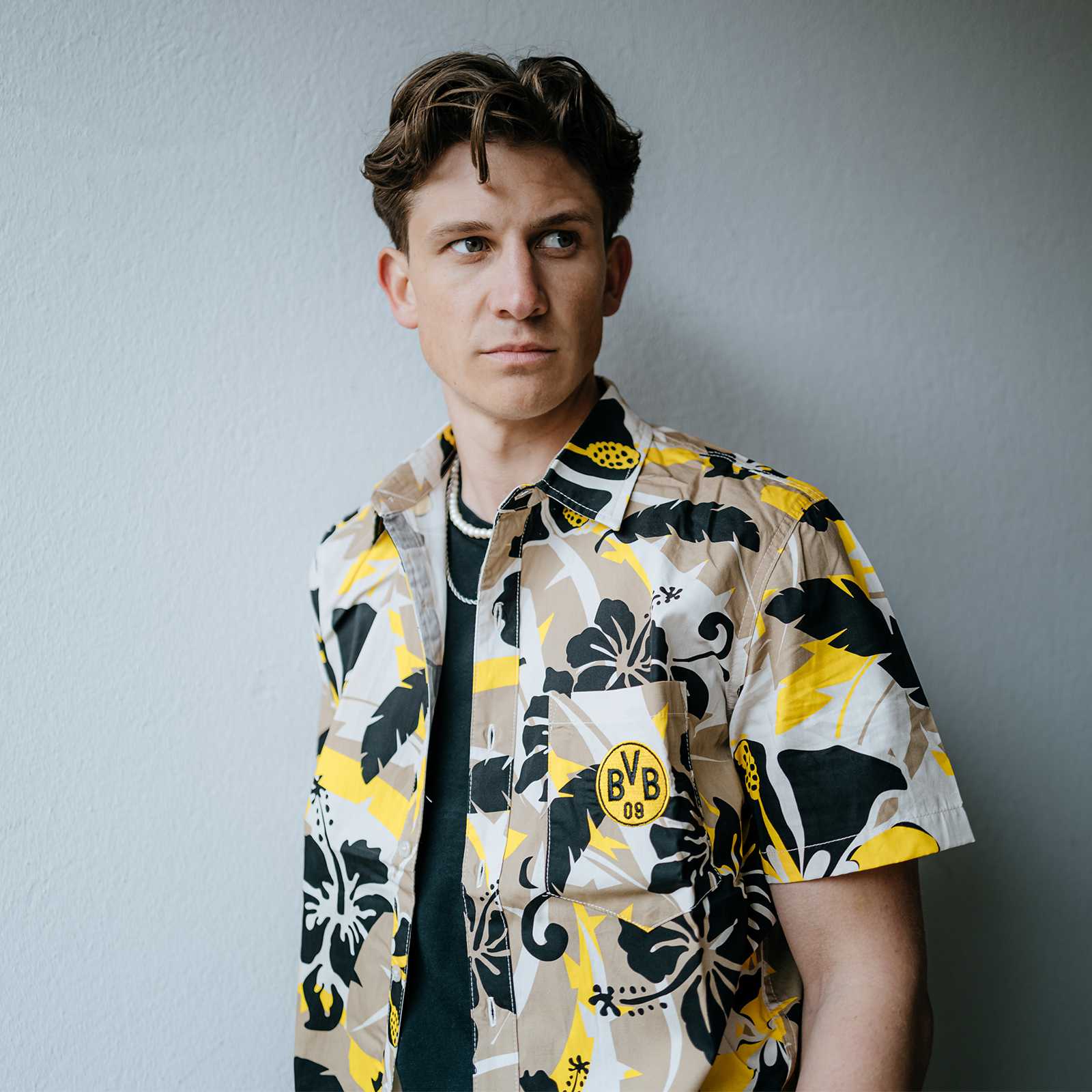 Ein Mann trägt das BVB Hemd Maui in der Vorderansicht; das kurzärmelige Hemd mit floralen schwarzgelben Mustern zeigt das BVB-Emblem auf der Brusttasche.