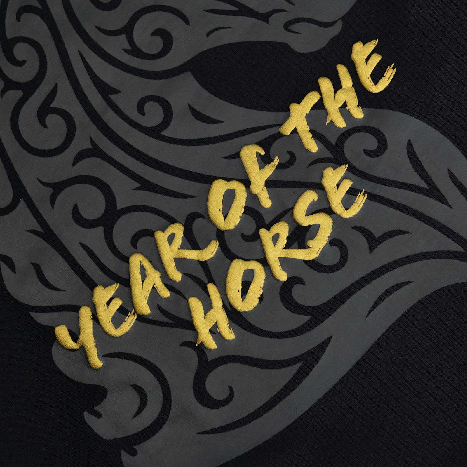 Detailansicht des grauen Pferde-Tattoo-Motivs und des goldenen Schriftzugs Year of he Horse auf dem Rücken.