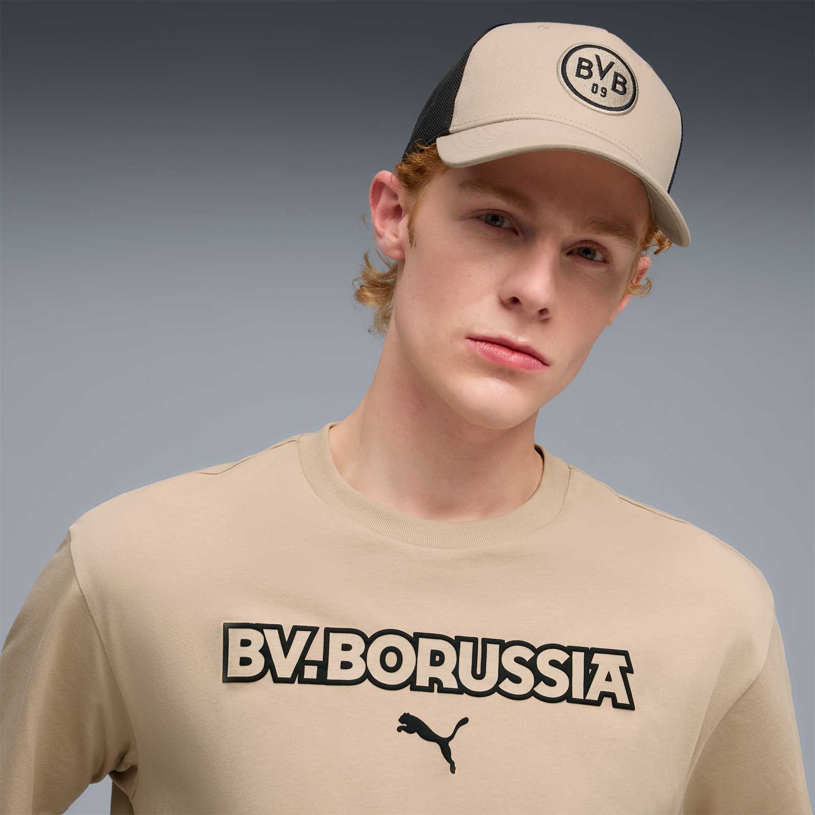Junges männliches Model trägt die beige BVB-Kappe mit Logo überm Schirm.