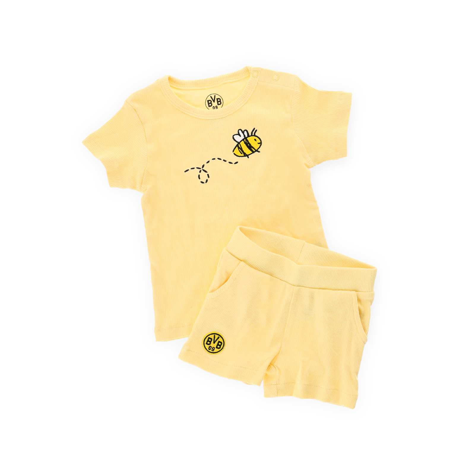 Die Vorderansicht des Rip-Sets bestehend aus einem hellgelben T-Shirt mit Bienen-Motiv und einer hellgelben Shorts mit BVB-Logo auf dem Bein