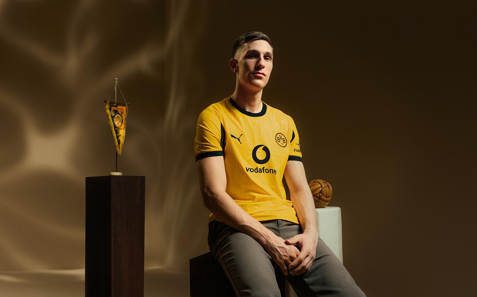 Nico Schlotterbeck sitzt in dem Cuptrikot 25/26 auf einem Hocker